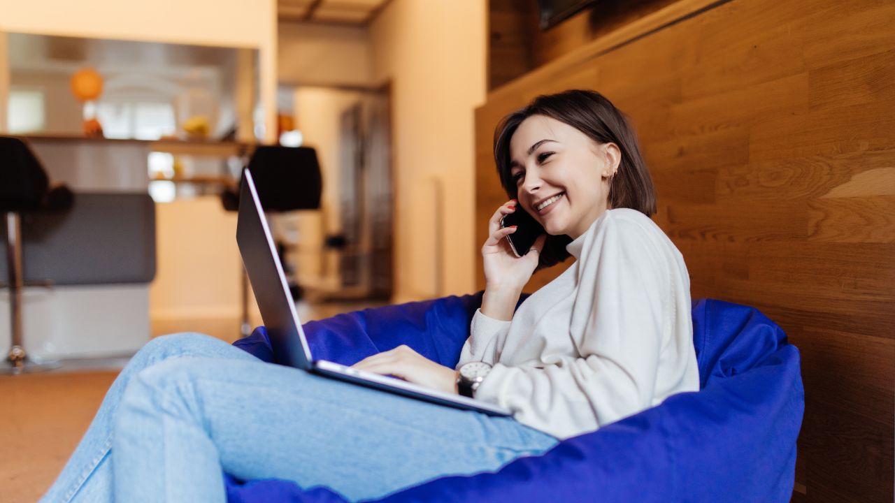 Women smiling on phone call with laptop on her lap