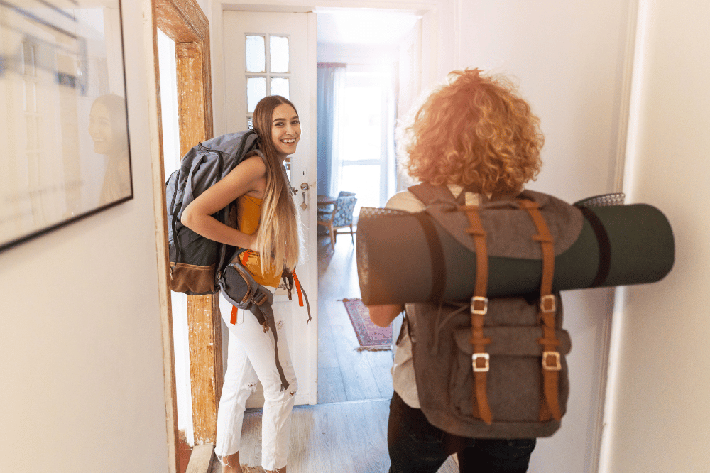 Two females walking with backpacks in hostel hallway