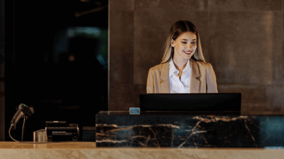 Portrait of young hotel receptionist behind counter